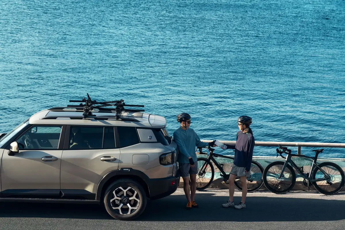 SUV équipé d’un porte-vélos de toit, deux cyclistes à côté