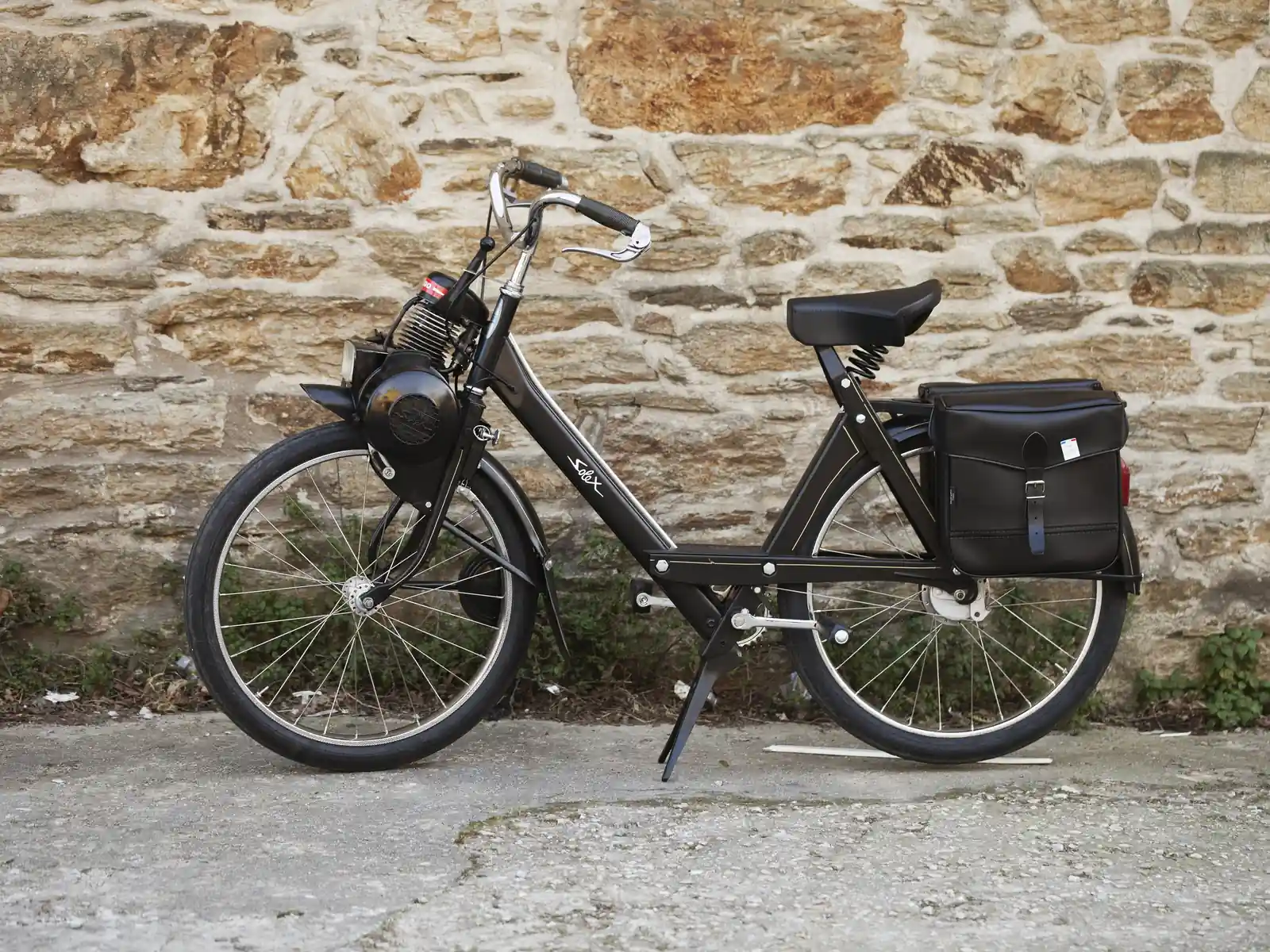 VéloSolex noir de profil, moteur au-dessus de la roue avant