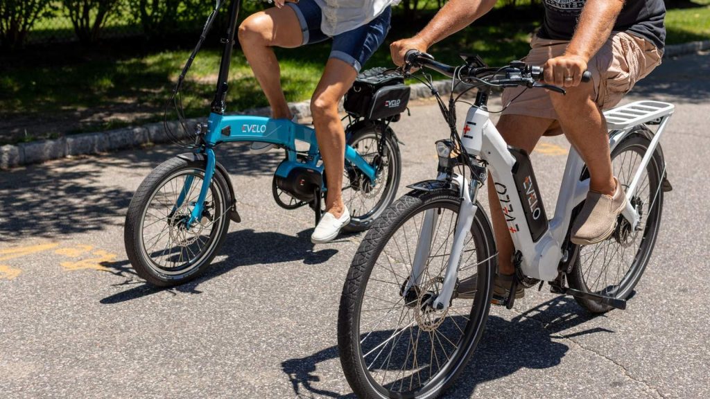 Deux cyclistes sur des vélos à assistance électrique, dont un modèle pliant bleu