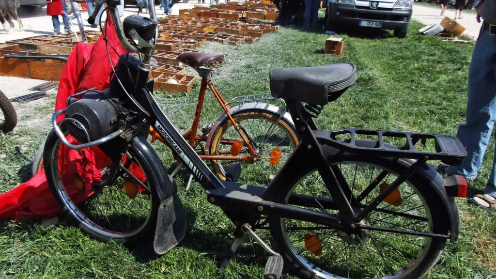 VéloSolex 3800 sur l'herbe lors d'une bourse aux pièces, étals en arrière-plan