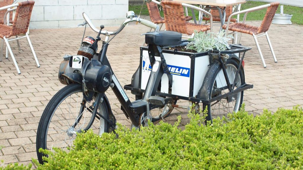 VéloSolex noir garé sur une terrasse, porte-bagages chargé d'une caisse