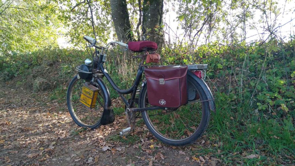 VéloSolex ancien garé sur un chemin de sous-bois avec sacoches