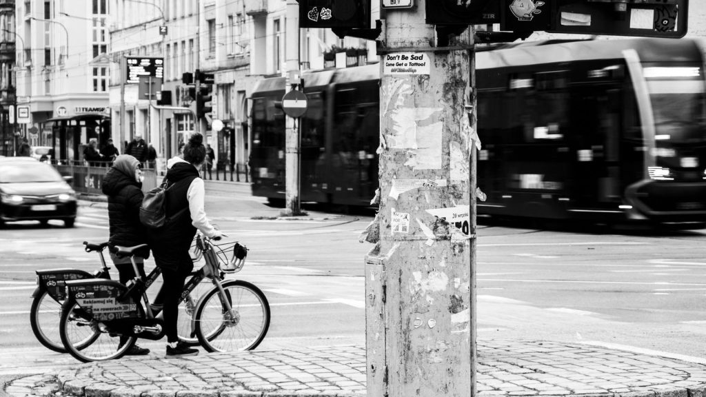Cyclistes à l'arrêt à un feu dans une rue de ville, devant un tramway