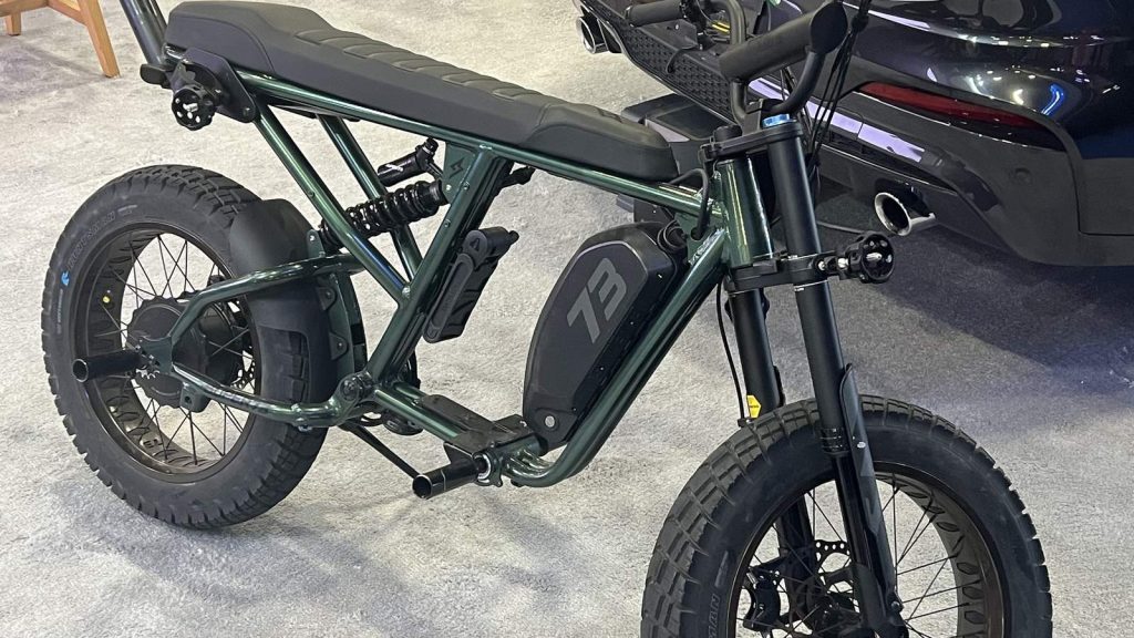 Vélo électrique de style moto à gros pneus, exposé sur un stand de salon