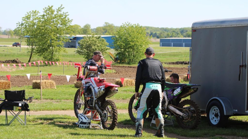 Motos de cross près d'une remorque fermée sur un terrain